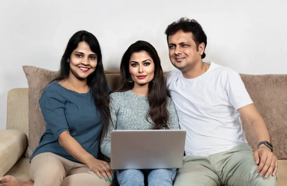 Three adults on a couch with a laptop, possibly researching term plans.